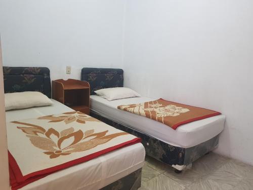 two beds sitting next to each other in a room at OYO 93237 Hotel Triarga in Takengon