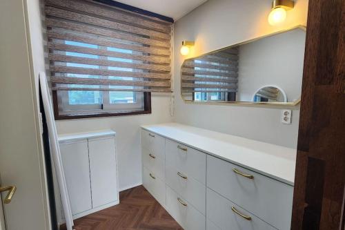 a kitchen with white cabinets and a mirror at Feel House in Goyang