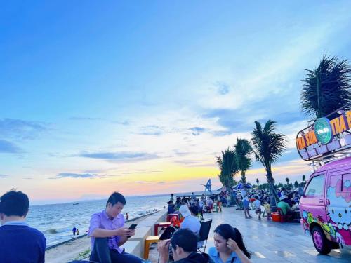 a group of people on a beach with a pink van at Homestay YẾN HÒA in Ấp Bình Hưng