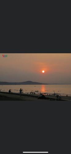 a sunset at the beach with people walking on the beach at Homestay YẾN HÒA in Ấp Bình Hưng