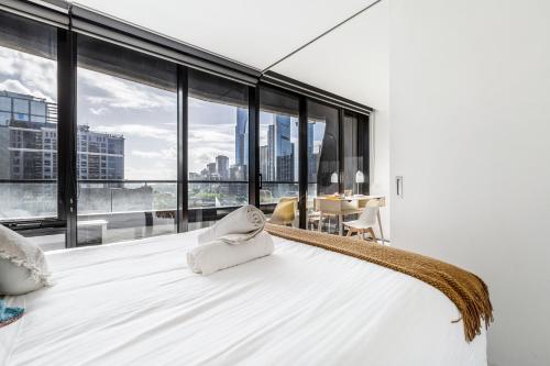 a bedroom with a large white bed with a large window at Riverview Suites by EdgeTrip in Melbourne
