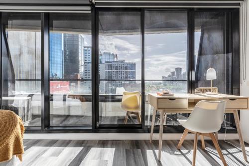 a room with a desk and chairs and large windows at Riverview Suites by EdgeTrip in Melbourne