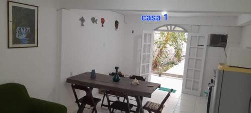 une chambre avec une table, des chaises et une porte ouverte dans l'établissement Areia Branca / Casa 1/ casa 2, à Cabo Frio