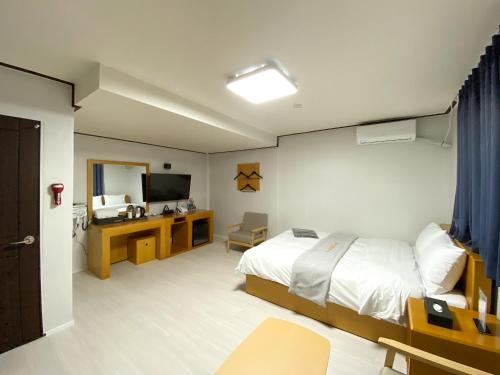 a bedroom with a bed and a desk and a television at Suanbo Hot Spring Healing Hotel in Chungju