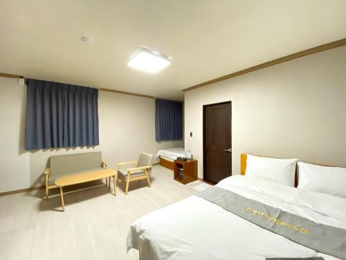 a bedroom with two beds and a desk and a chair at Suanbo Hot Spring Healing Hotel in Chungju
