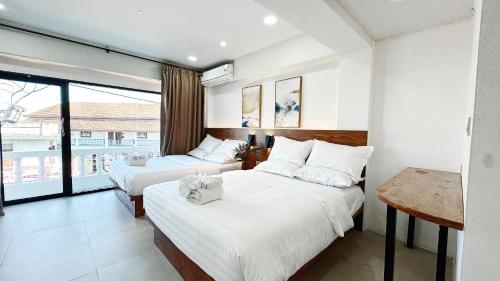 a hotel room with two beds and a balcony at Key酒店@古城中心店 in Chiang Mai