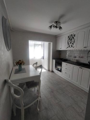 cocina con armarios blancos, mesa y sillas en Apartament Bzg 1 en Rădăuţi