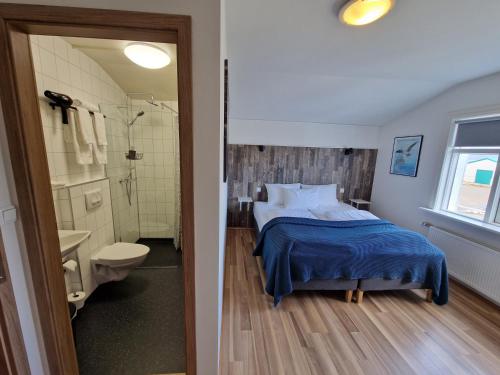 a bedroom with a bed and a bathroom with a shower at Guesthouse Mikael in Höfn