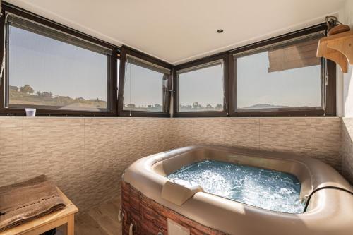 una vasca da bagno in una stanza con finestre di Vineyard Cottage Grajska Kašča - Happy Rentals a Mirna