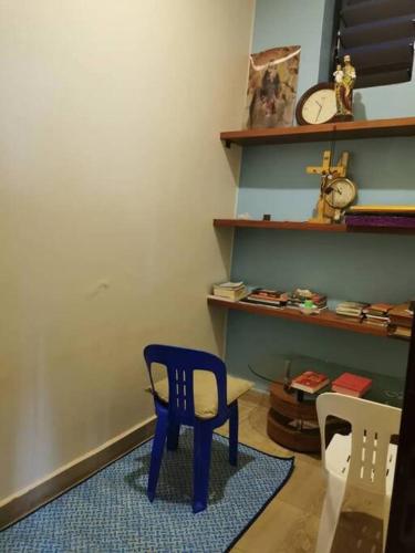 a blue chair in a room with a clock on a shelf at Cheerful 3 Bedroom house with ample parking space. in Kampala