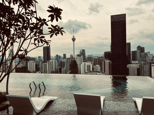 a swimming pool with chairs and a city skyline at KLCC Suites At Axon Residence in Kuala Lumpur