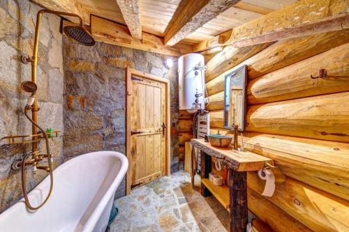 uma casa de banho com uma banheira e uma parede de madeira em ECO HOUSES ART OF LIVING - Еко къщи изкуството да живееш em Pamporovo