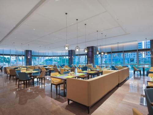 ein Restaurant mit Tischen und Stühlen und Fenstern in der Unterkunft Hampton by Hilton Guangzhou Wenchong in Guangzhou