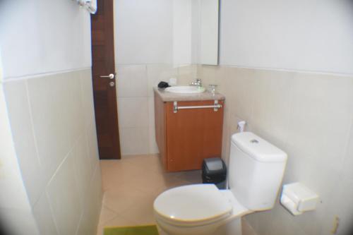 a bathroom with a white toilet and a sink at Dabumito Guest House in Canggu