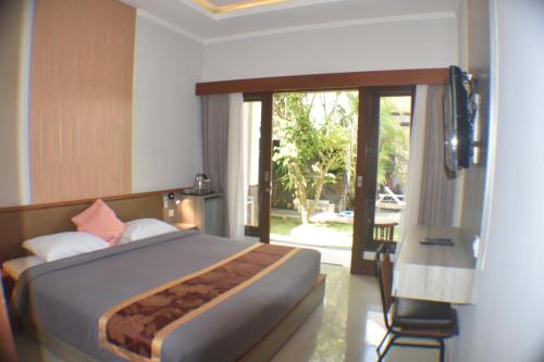 a bedroom with a bed and a sliding glass door at Dabumito Guest House in Canggu