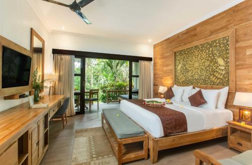 ein Schlafzimmer mit einem großen Bett und einem TV in der Unterkunft Manah Shanti Suites by Pramana Villas in Ubud
