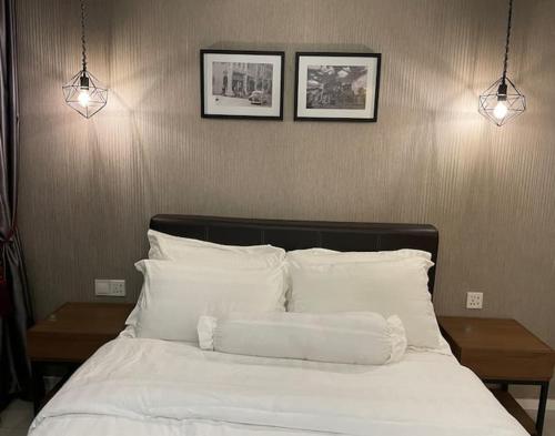 uma cama com almofadas brancas e duas fotografias na parede em IPOH 8Perkins Canning Garden 7-8pax Elegant Homestay with 4Bedrooms, 3Bathroom, 1Living, 1Dining, 1Kitchen-Bar with 3Parkings em Ipoh