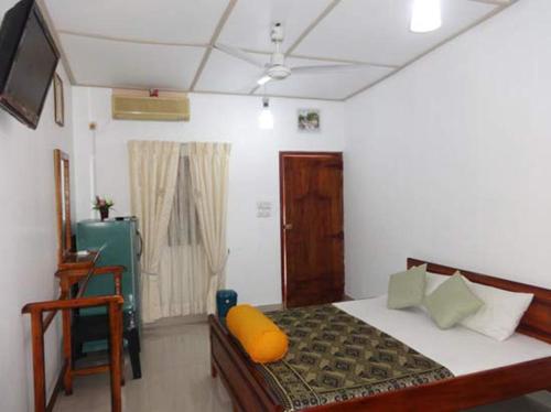 a bedroom with a bed with a yellow pillow on it at Dutch Bay Beach Cottages in Trincomalee