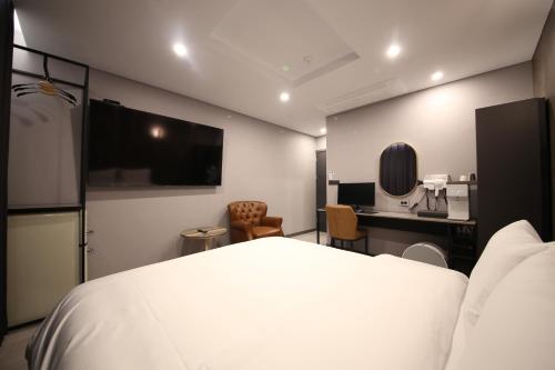 a hotel room with a white bed and a desk at Stay Oneul in Gongju