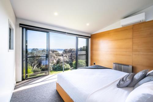 1 dormitorio con cama grande y ventana grande en Footprints 2, en Coles Bay