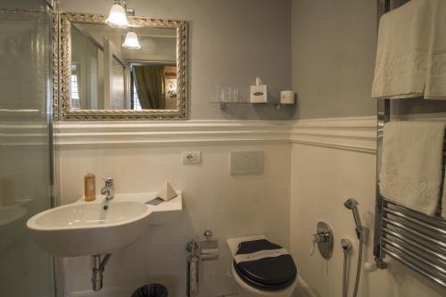 a bathroom with a sink and a toilet and a mirror at Palazzo Pacini in Colle Val D'Elsa