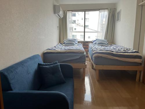 a room with three beds and a couch and a window at Shine house in Toda