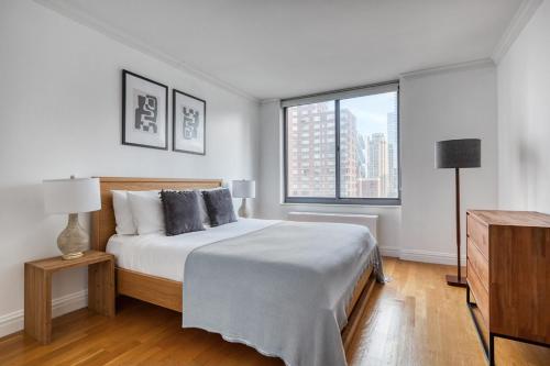 a white bedroom with a bed and a window at Midtown 1BR w Water views Indoor pool NYC-36 in New York