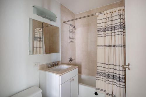 a bathroom with a sink and a shower curtain at Midtown 1BR w Water views Indoor pool NYC-36 in New York