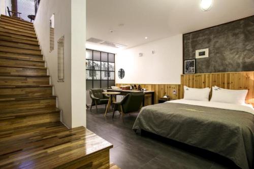 a bedroom with a bed and a table and a staircase at Hotel The Jaja in Gongju