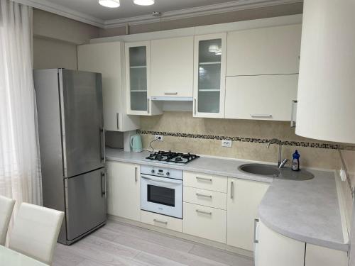 a kitchen with white cabinets and a stainless steel refrigerator at Комфортабельная квартира на улице Василе Лупу in Chişinău