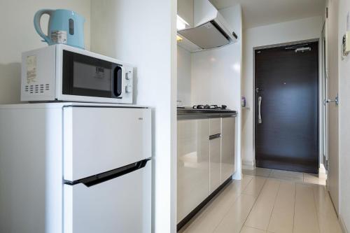 eine Küche mit einer Mikrowelle auf dem Kühlschrank in der Unterkunft Tenjin Minami San Ban Kan in Fukuoka