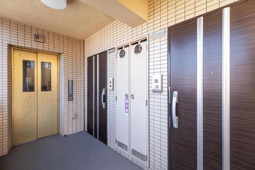 einen Flur eines Gebäudes mit zwei Schließfächern und einer Tür in der Unterkunft Tenjin Minami San Ban Kan in Fukuoka