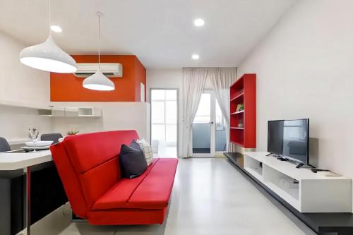 a living room with a red chair and a desk at Straits Garden Suites Penang in Jelutong