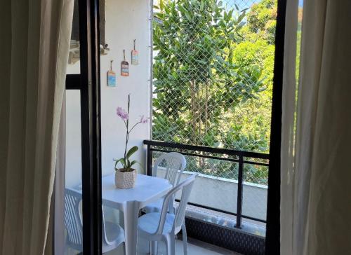 Apartamento Área Nobre no Recreio dos Bandeirantes في ريو دي جانيرو: طاولة بيضاء وكراسي على شرفة مع نافذة