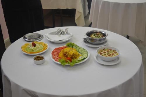 ein weißer Tisch mit Teller mit Lebensmitteln drauf in der Unterkunft Kashmir lodge in Muzaffarabad