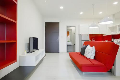 a living room with a red couch and a kitchen at Straits Garden Suites Penang in Jelutong