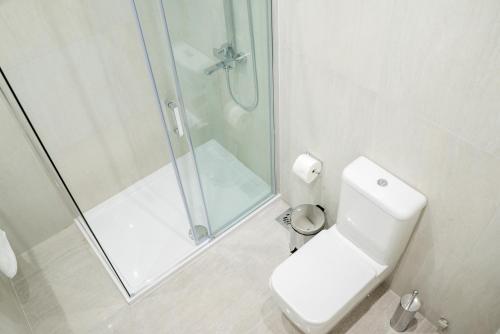 a white bathroom with a shower and a toilet at Casino Motel Senator in Gevgelija