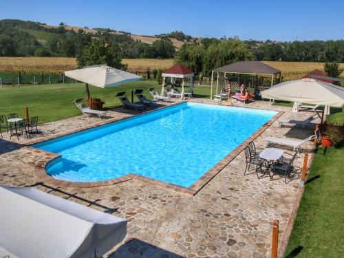 una piscina con sedie e ombrelloni in un cortile di Apartment on farm amidst the Umbrian hills a Todi