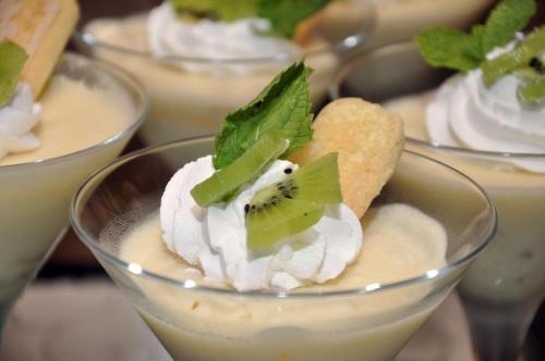 a group of desserts in bowls with whipped cream and kiwi at Pensiunea Muntele Verde in Slănic