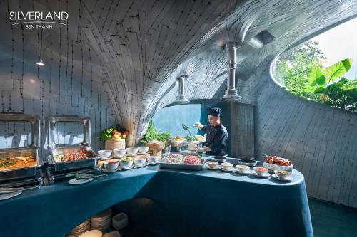 a man standing behind a buffet table with food at Silverland Bến Thành in Ho Chi Minh City
