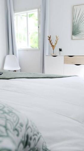 a white bedroom with a bed and a window at Coastal Home in Tamarin, AC, Wi-Fi, Walk to Everything in Tamarin in Tamarin