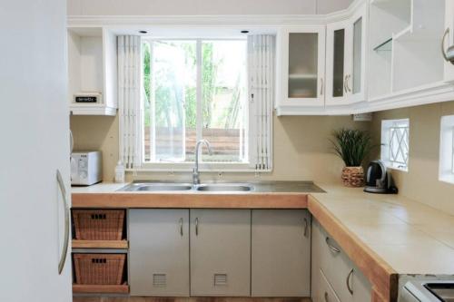 a kitchen with white cabinets and a sink and a window at Tamarin River Villa in Tamarin