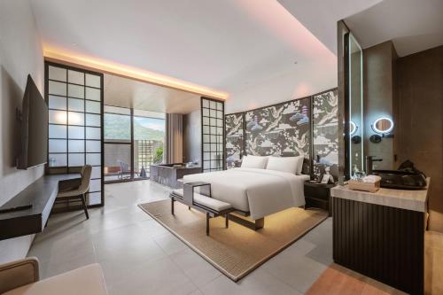 1 dormitorio con cama, escritorio y baño en Tengchong Jingge Banshan Hot Spring Hotel, en Tengchóng