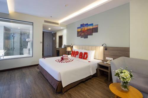 a bedroom with a large white bed and a couch at Xavia Hotel in Nha Trang
