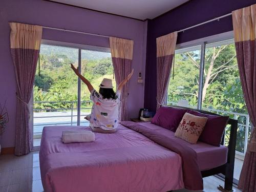 Dziewczyna stoi na łóżku i patrzy przez okno. w obiekcie Dr. House w mieście Khao Kho