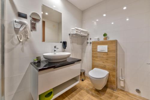 a white bathroom with a sink and a toilet at BuzzStays - Spa & Wellness Hotel - Privately Managed Apartments in Zlatibor