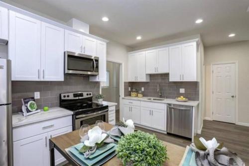 a kitchen with white cabinets and a table in it at San Jose Shark House - Unit 1 in San Jose