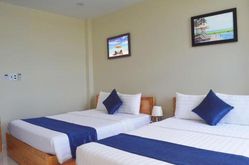 a bedroom with two beds with blue and white pillows at Lucky Star Ho Tram Hotel & Restaurant in Ho Tram