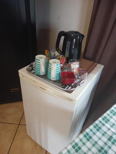 a coffee pot and dishes on top of a refrigerator at Africa Dawn Guesthouse in Musina