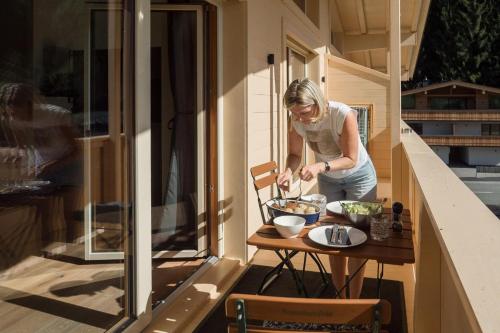 a woman standing on a balcony cooking food on a table at Alte Bildhauerei in Aurach bei Kitzbuhel